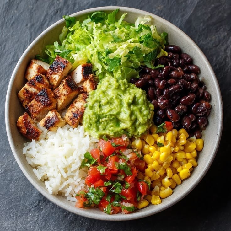 Quick rice bowl with chicken, beans, corn, lettuce, salsa and guacamole