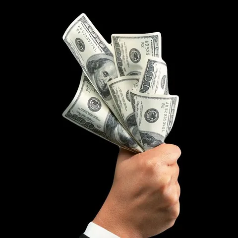 Hand holding a fan of US hundred-dollar bills against a black background